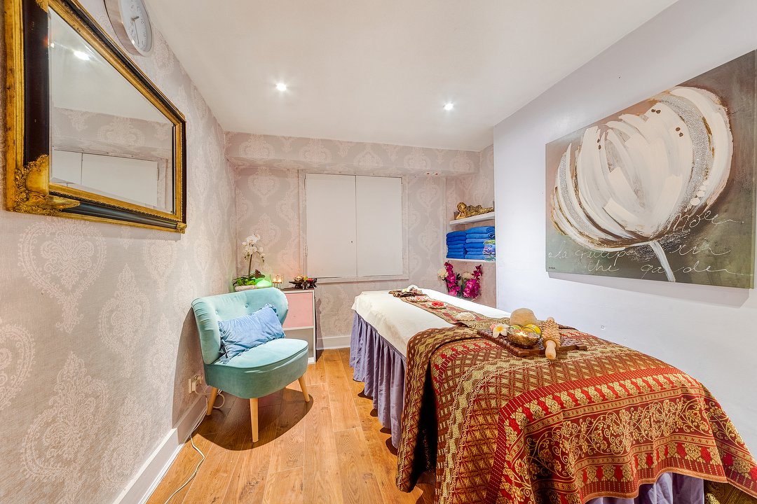 The treatment room at 19 Thai Massage on Farringdon Road, with a massage bed and red and gold Thai textiles